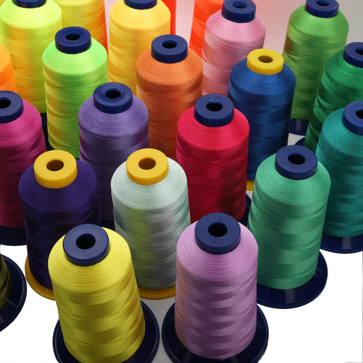 A collection of multi-colored polyester embroidery thread spools in various shades of yellow, green, orange, pink, and purple
