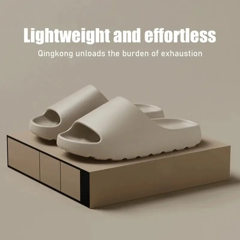 A pair of beige cloud thick-soled EVA slides resting on a wooden block.