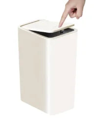 A hand is lifting the lid of a white pop-up slim trash can.