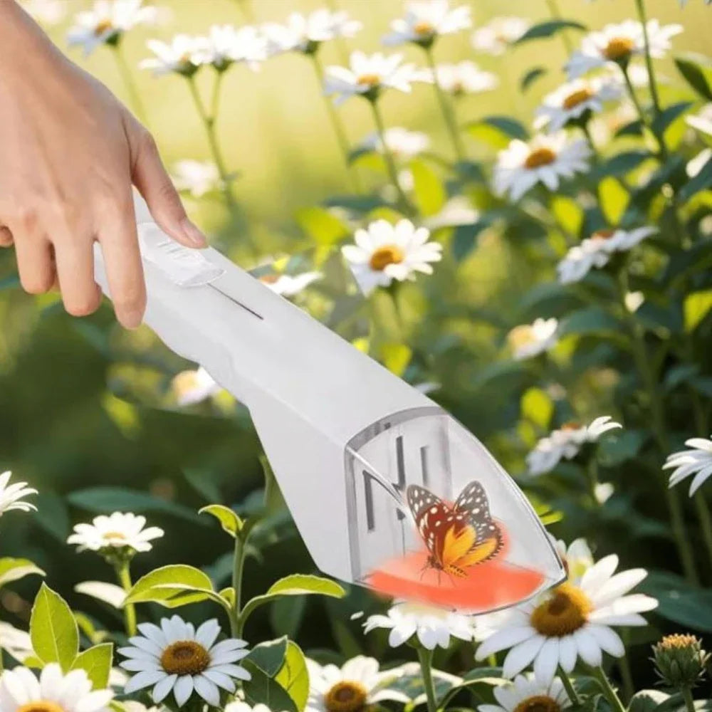 A hand is holding a white handheld insect catcher clamp tool in a sunny garden filled with white and yellow flowers.