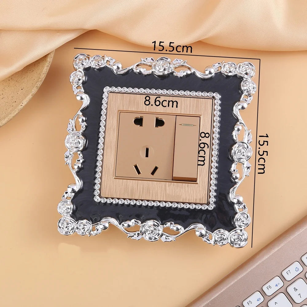 A square switch cover frame with a rose pattern border and brass accents, shown on a light background.