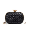 A black handwoven woven clutch bag with a gold chain strap.