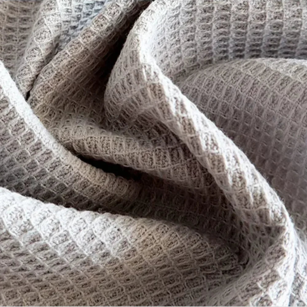 A close-up of a set of four light beige pure cotton waffle weave towels folded and draped.