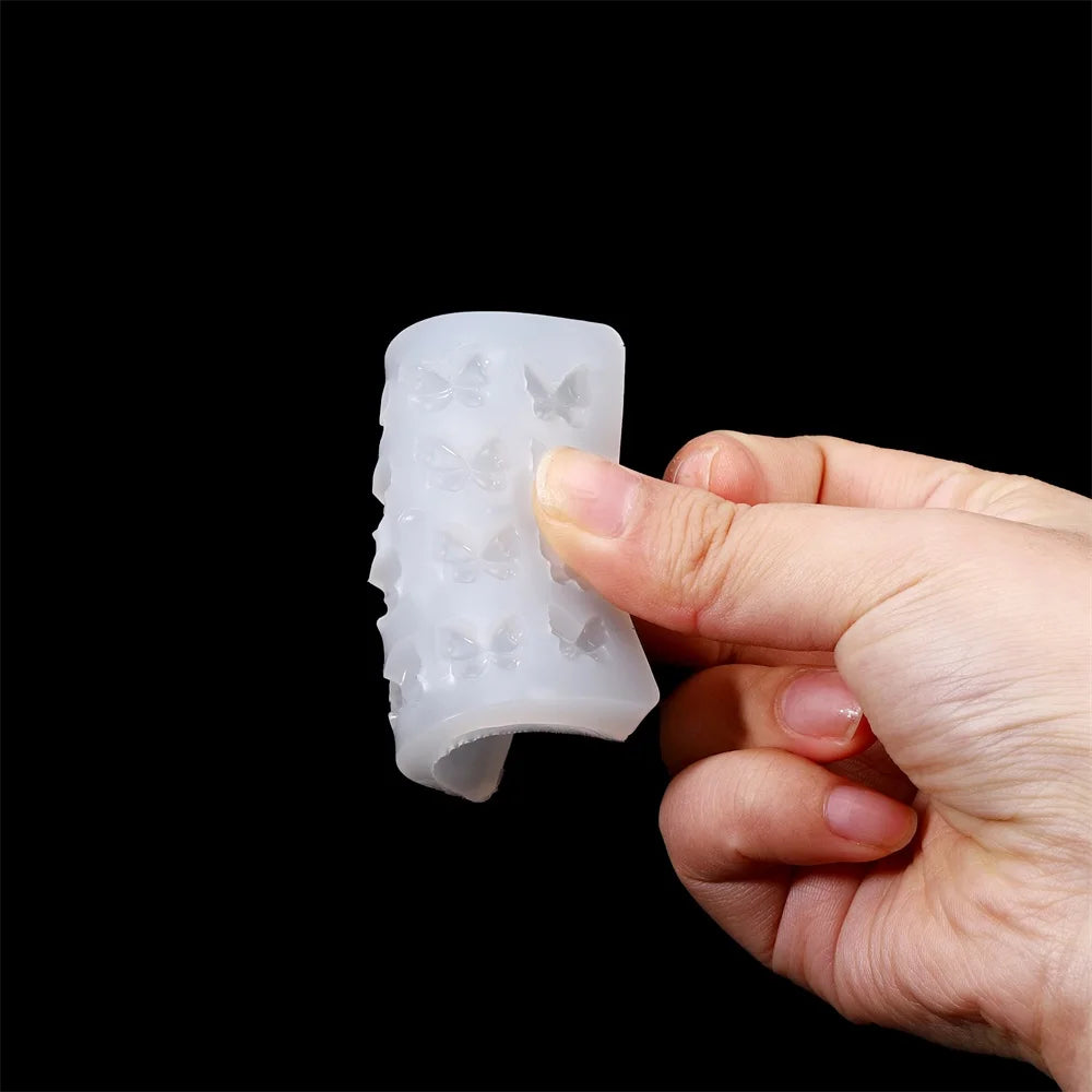 A hand holds a white butterfly shape epoxy resin mold for DIY jewelry making against a black background.