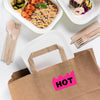 A brown paper bag with a pink sticker labeled HOT, next to wooden cutlery and food