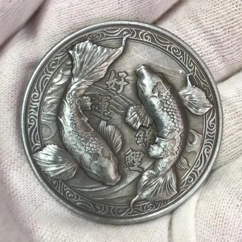 Silberner antiker chinesischer Koi-Glücksgroschen mit detailliertem Fischdesign, in der Hand gehalten.