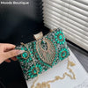 A green rhinestone evening clutch with a gold chain strap is displayed on a black background.