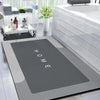A modern bathroom featuring a large white bathtub and a rectangular mat with the word HOME engraved on it.