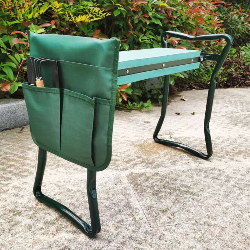 A dark green heavy duty foldable garden kneeler seat with a tool pouch and metal frame sitting on concrete.