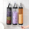Wall-mounted mesh bag dispenser with three colored bags, including purple, green, and orange.