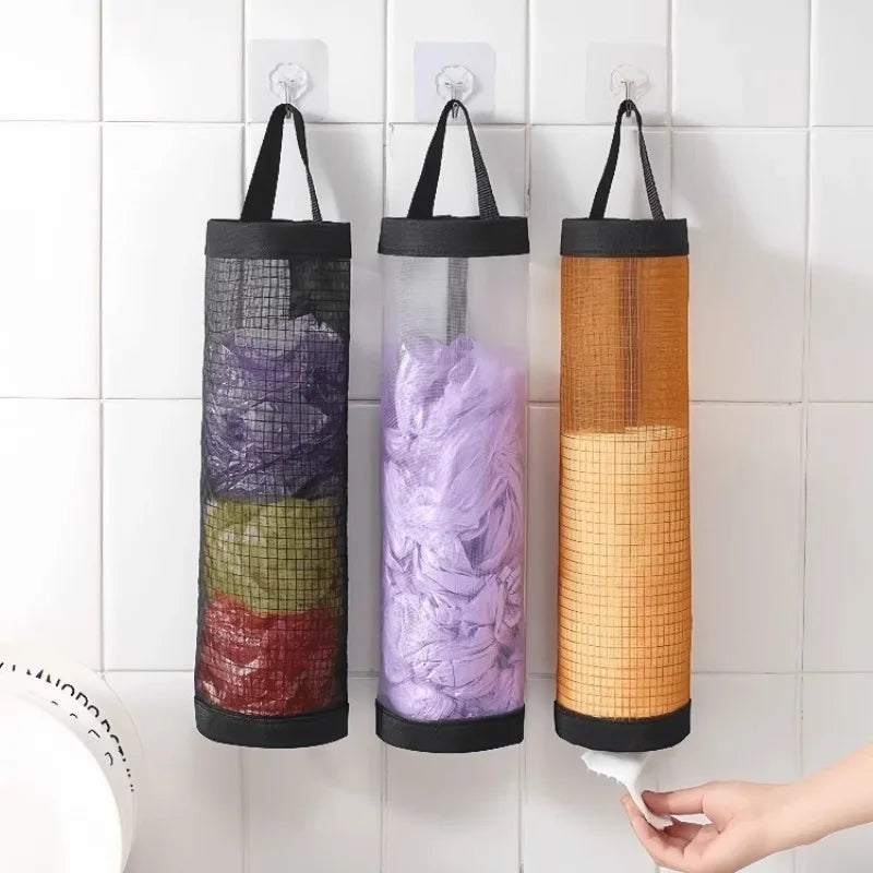 Wall-mounted mesh bag dispenser with three colored bags, including purple, green, and orange.