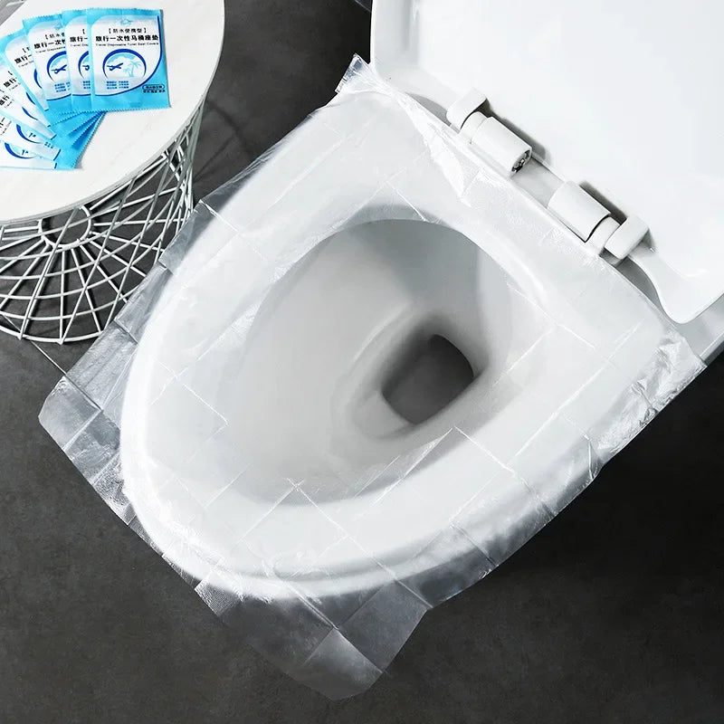 A white toilet seat is covered with a clear plastic disposable cover, showing a pack of blue instruction cards nearby.