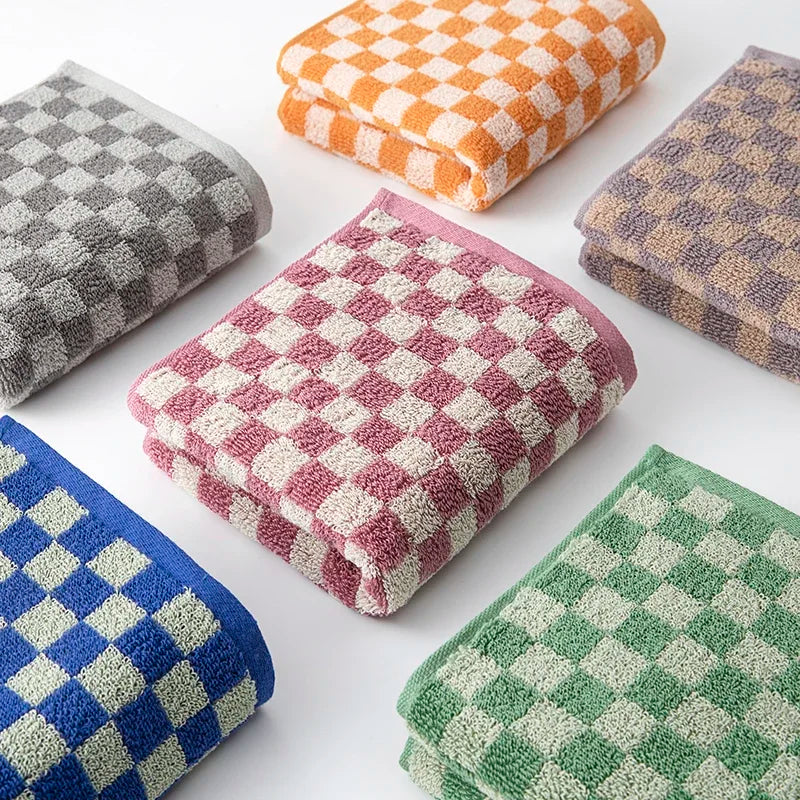 A set of plaid cotton bath towels in various colors including orange, gray, pink, and green.