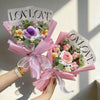 A bouquet of handmade crochet artificial flowers in pink and green, wrapped in sheer pink paper.