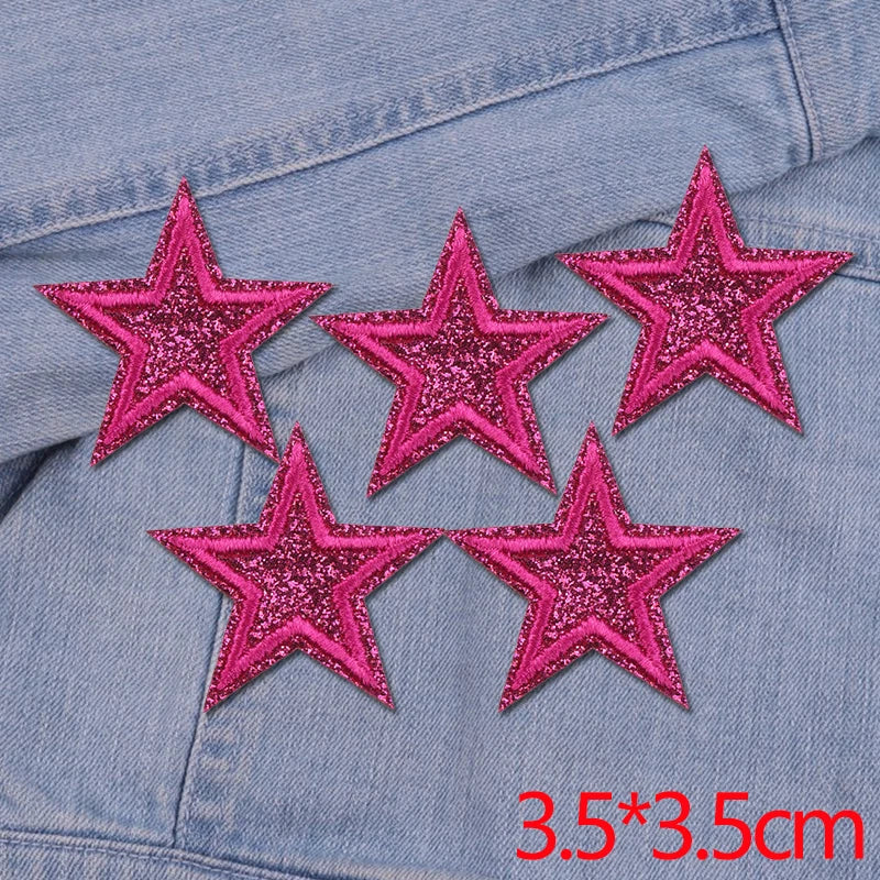 Set of five pink glitter star iron-on embroidered patches on a denim fabric.
