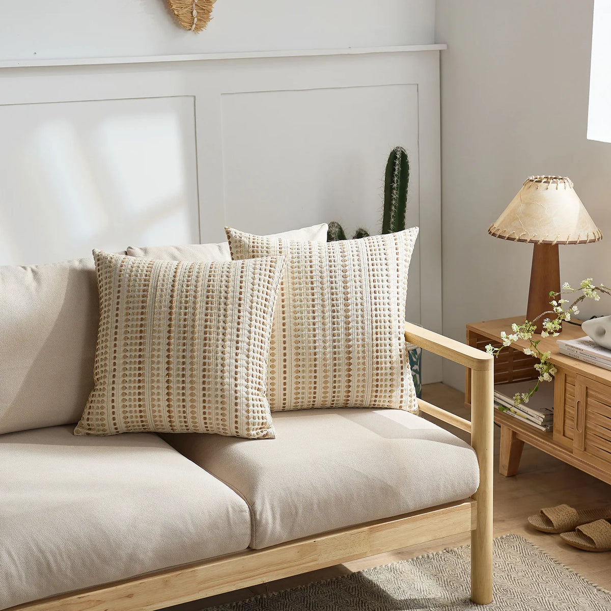 A set of two beige woven linen pillow covers displayed on a light wood sofa.