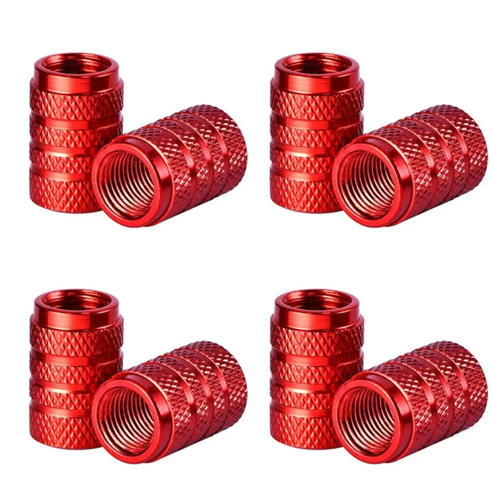 A set of four knurled red aluminum tire valve caps shown in various angles.