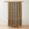 A brown and black leopard print shower curtain hanging from a gold rod.