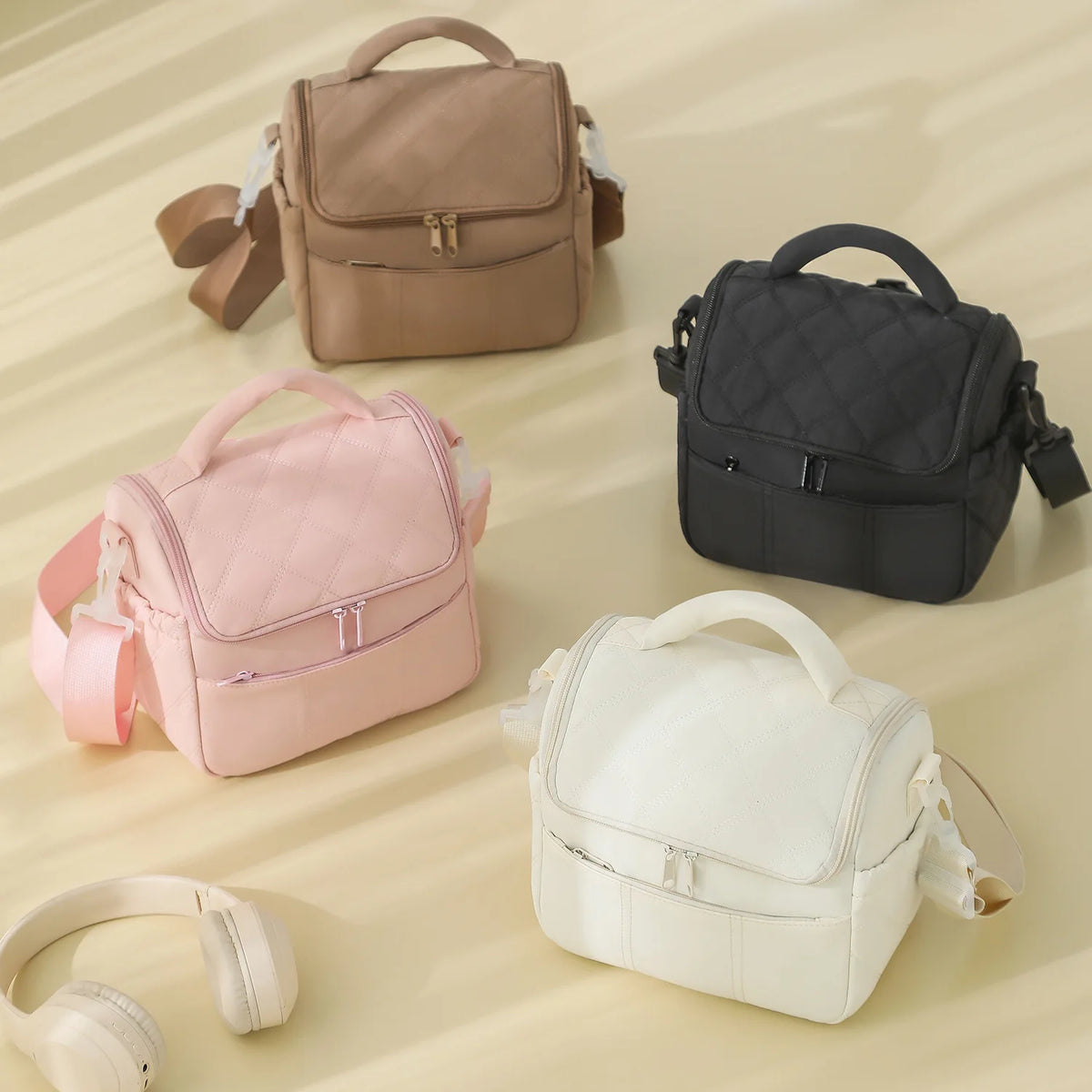 Three insulated leakproof nylon lunch bags in beige, black, and white are displayed on a light surface.