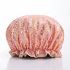 A reusable elastic shower cap for women in pink fabric with gold leopard print.