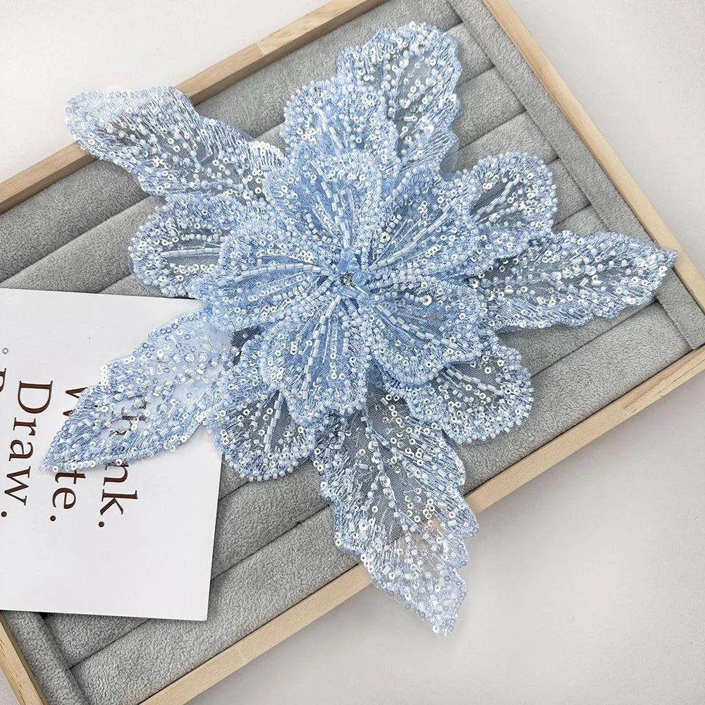 Light blue sequin floral lace applique patch for sewing and DIY crafts displayed on a wooden board.