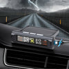 A black tire pressure monitoring device is mounted on a car's dashboard, set against a dramatic stormy landscape.