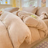 A beige cozy milk velvet bedding set featuring a duvet cover and pillows on a bed.