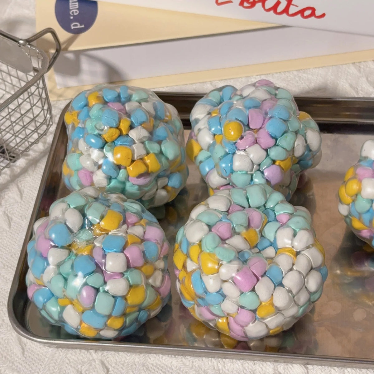 A collection of colorful, squishy sensory stress balls in various pastel shades resting on a metal tray.