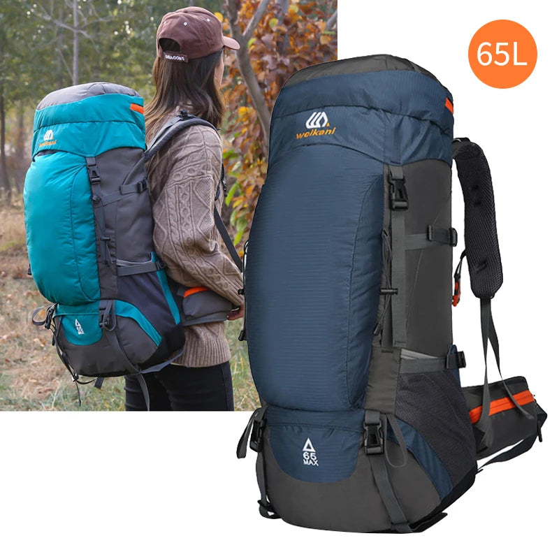 A dark blue 65L waterproof hiking backpack being worn by a person outdoors.