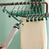 A set of five anti-slip stainless steel hangers with clips hanging on a wooden rack.