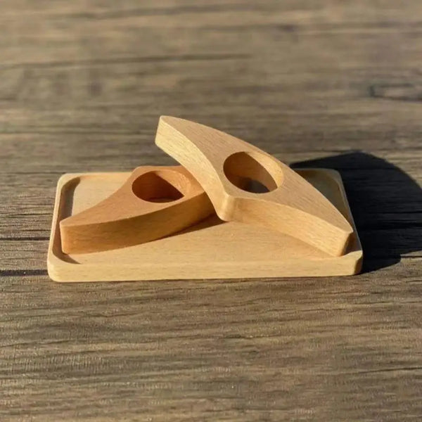 Ein ergonomischer Buchseitenhalter aus hellem Holz mit zwei Fächern liegt auf einer Holzoberfläche.