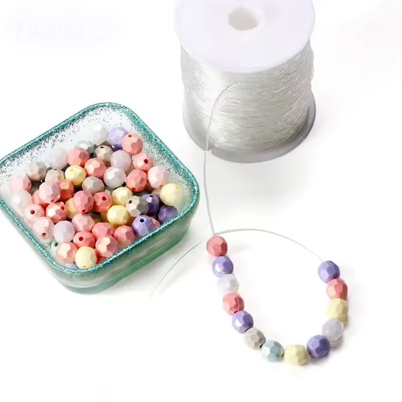 A spool of silver elastic cord and a string of colorful beads for jewelry making