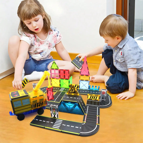 Deux jeunes enfants jouent avec un ensemble de blocs de transport magnétiques jaunes et noirs sur un plancher en bois.