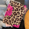 A leopard print floral tablet case for an iPad is held in a person's hand against a dark background.
