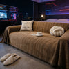 A brown fishbone pattern anti-slip sofa cover draped over a two-seat sofa in a modern room.