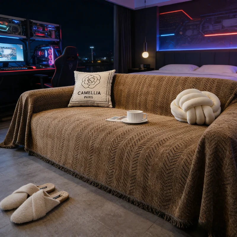 A brown fishbone pattern anti-slip sofa cover draped over a two-seat sofa in a modern room.