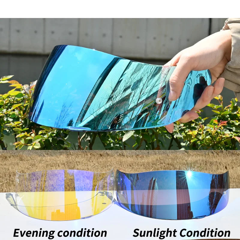 A hand holds a motorcycle helmet visor lens shield showing different light conditions, including evening and sunlight.