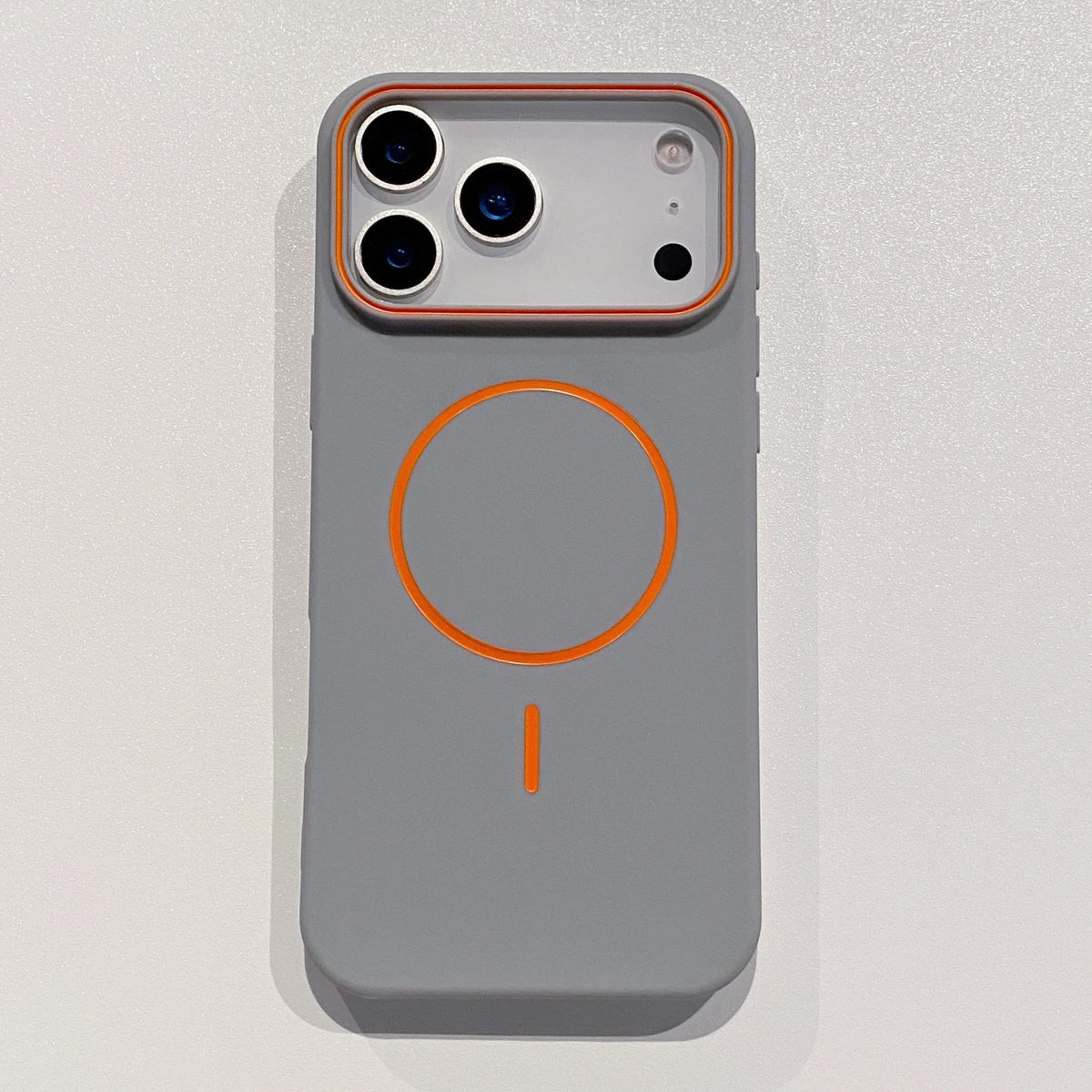 A matte gray phone case with an orange circular design and MagSafe support visible from the front.