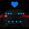 A black car's rear view shows blue heart stickers placed on the trunk and bumper.