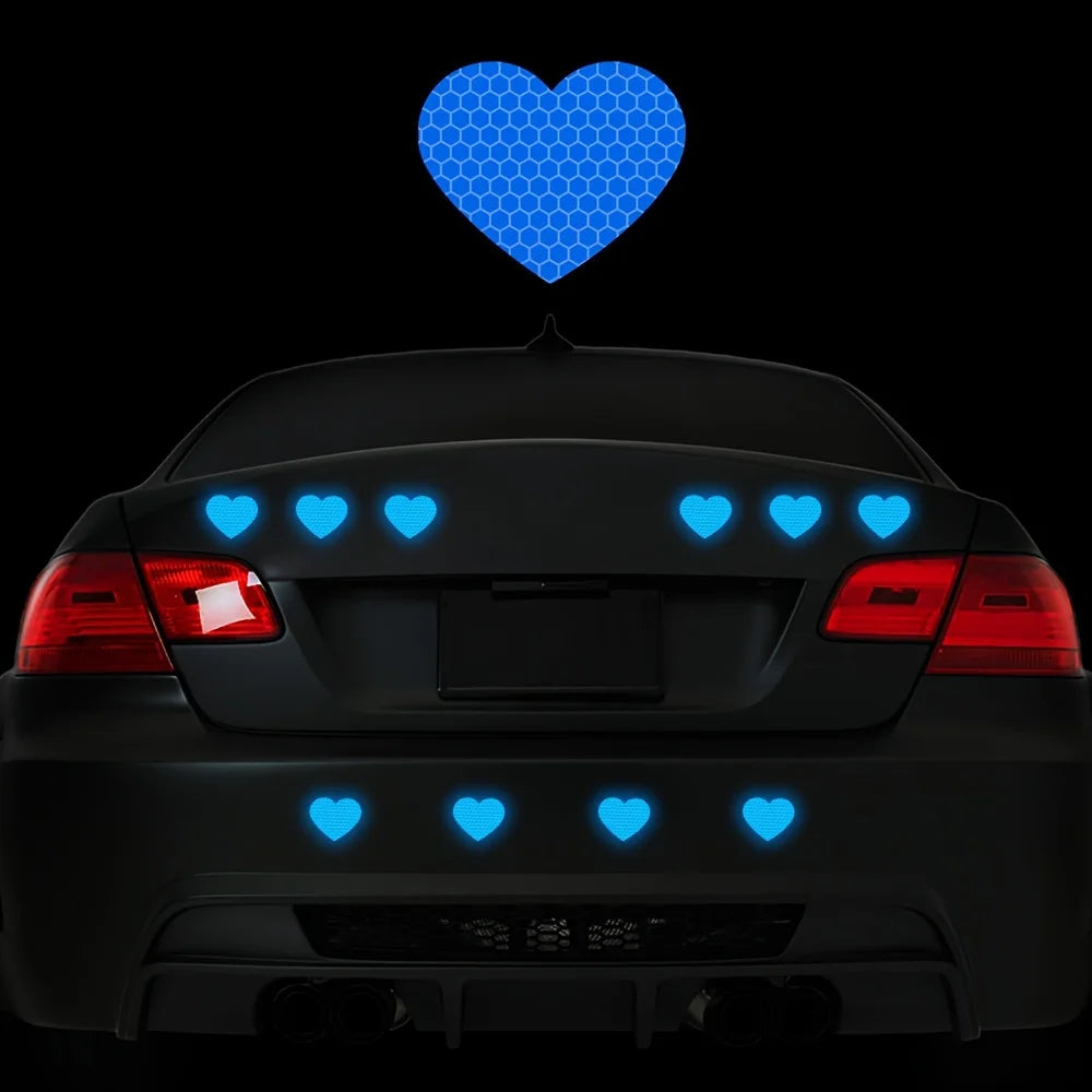 A black car's rear view shows blue heart stickers placed on the trunk and bumper.