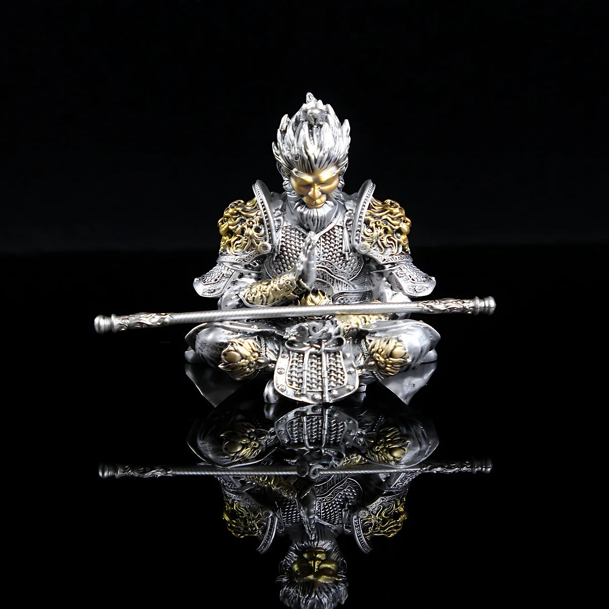 Silver hand-painted figurine of the Monkey King with staff, displayed against a black background.