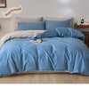 A light blue quilted duvet cover set with matching pillowcases on a bed.