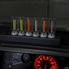 A row of glass tubes containing various colored LED filaments resting on a dark surface.