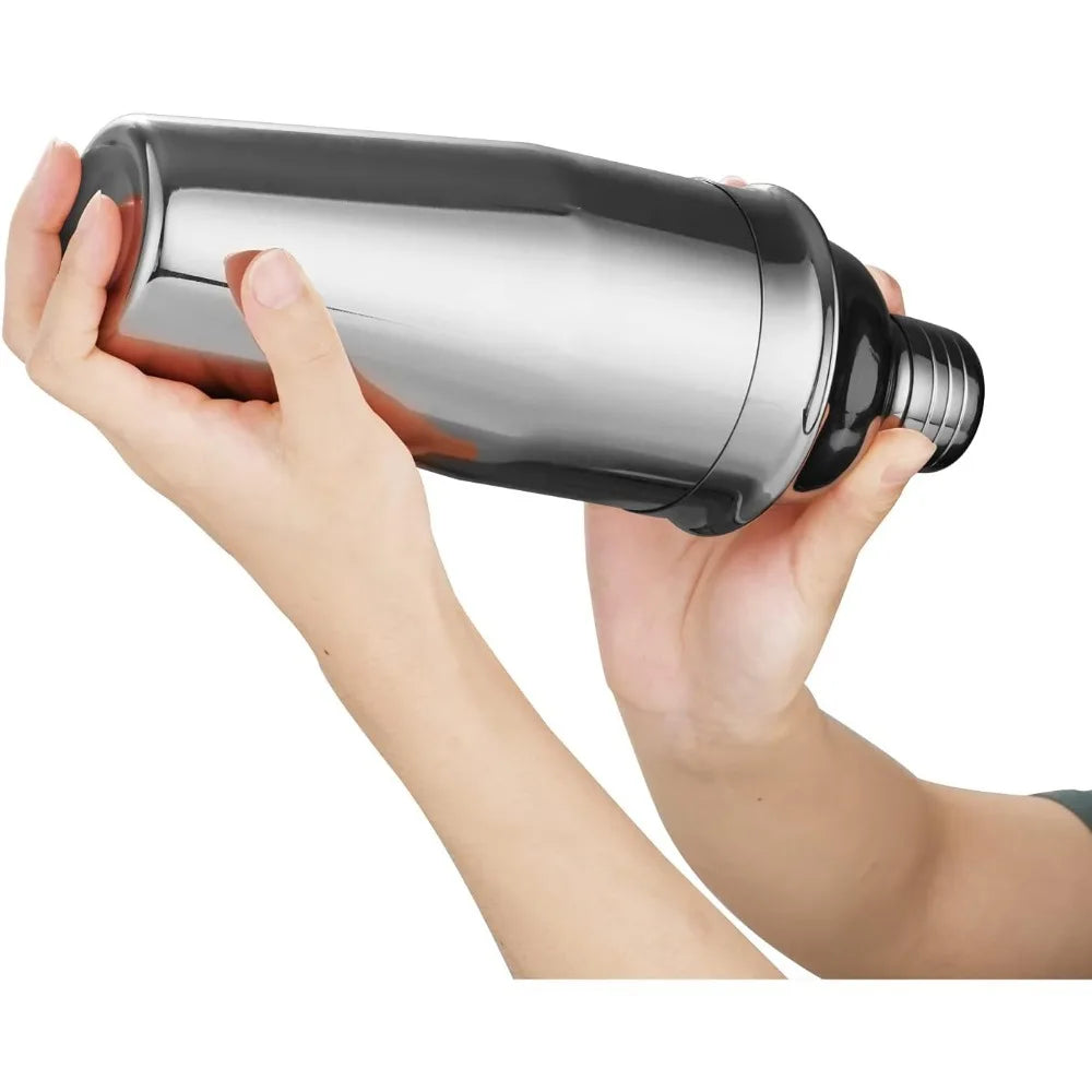 A hand is holding a shiny stainless steel cocktail shaker.