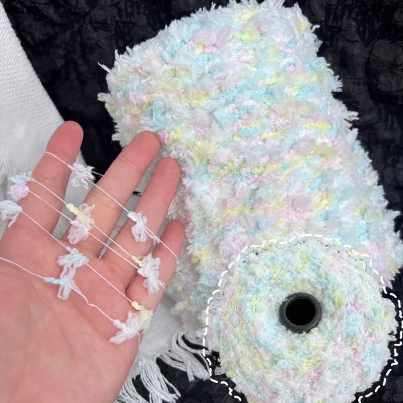 A hand is holding a ball of light blue and white variegated cotton blend yarn for knitting and crochet.