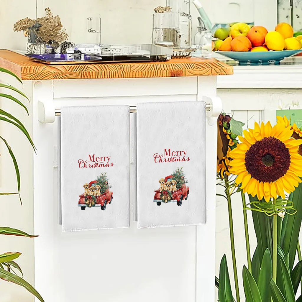 A set of two white kitchen towels featuring a festive Christmas design on red pickup trucks.