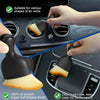 A hand is using a black detailing brush with soft bristles to clean air vents and gaps in a car interior.