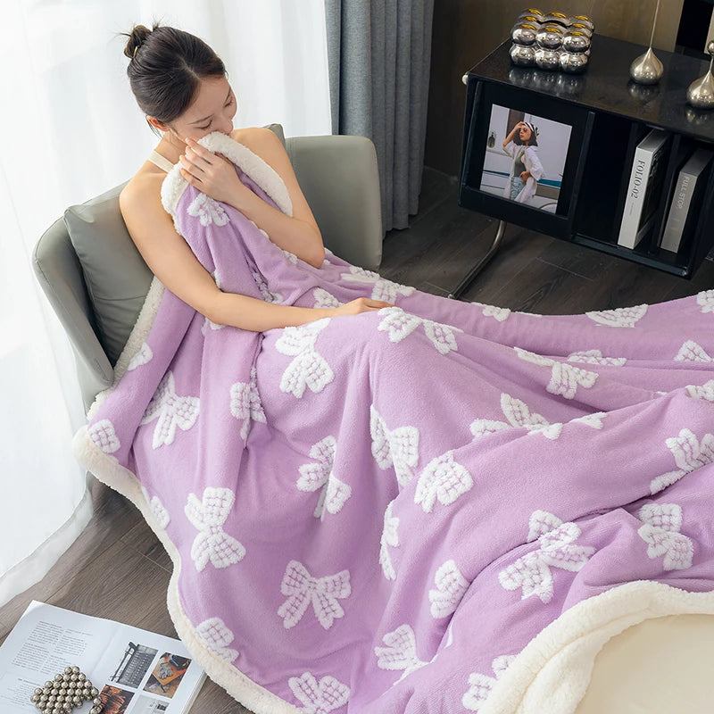 A purple plush jacquard throw blanket with white floral patterns draped over a person in a modern indoor setting.