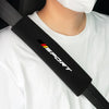 A black soft car seat belt cushion is shown against a white t-shirt.