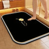 A black quick-dry diatomite bath mat with a yellow flower and heart design placed on a tiled floor.